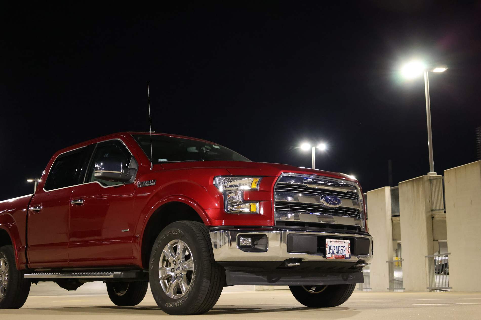 A red Ford F-150 Lariat parked on a rooftop deck in Austin at night